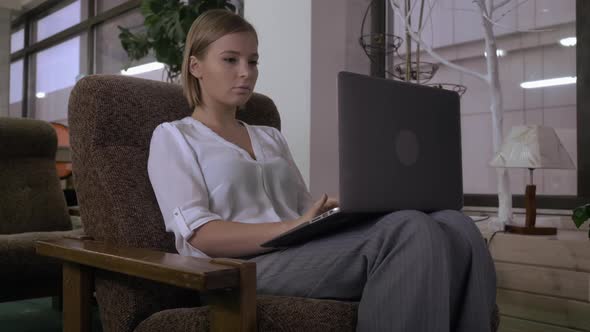 Woman Sitting on the Chair Near the Big Window Using Laptop