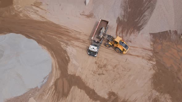 Excavator Loading Sand Into Large Truck Aerial View