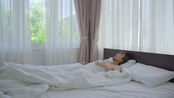 A Young Man in a Bed Feels That It's Very Hot