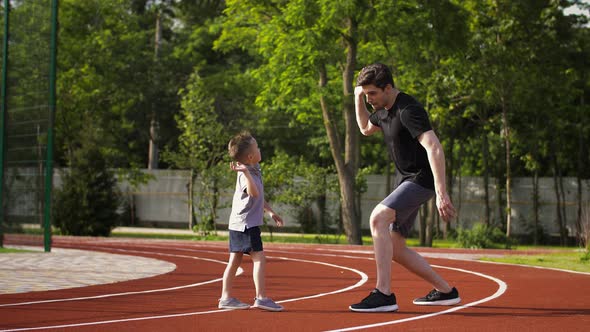 Athletic Young Dad and His Little Son in Sportswear are Smiling Giving a Five to Each Other After