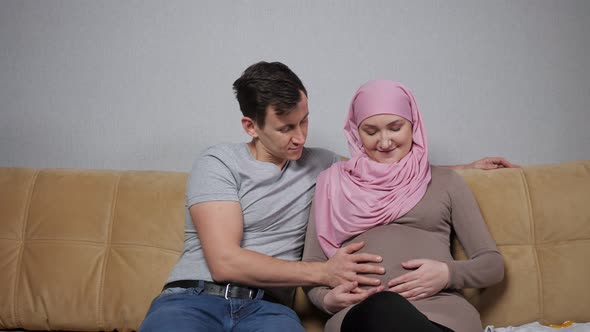Muslim Mother and Father Caress Pregnant Belly Smiling
