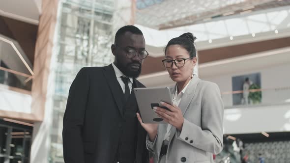 Colleagues with Tablet Discussing Work in Lobby