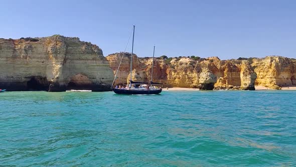 Sailing yacht in front of beautiful rock formations of the Algarve