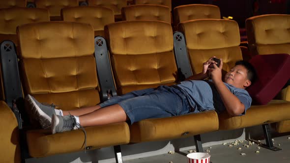 A Boy Laying Down and Playing Mobile Phone