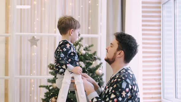 Happy Family of Father and Son Near Christmas Tree at Home