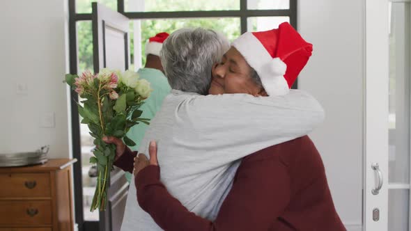 Two diverse senior female friends welcoming in doorway at christmas time