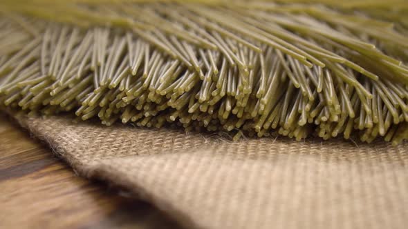 Organic vegetable raw uncooked spaghetti pasta on rustic burlap on a board