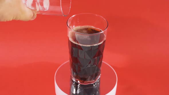 Pouring cola into glass with ice while spinning.