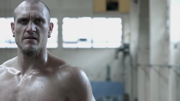 Portrait of a shirtless personal trainer man inside an abandoned building after a workout