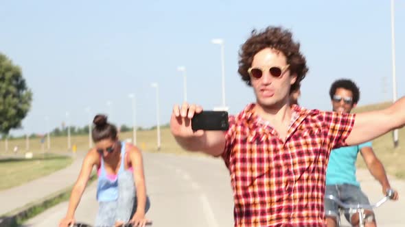 Three young adults having fun cycling and taking selfies