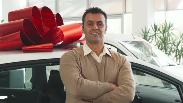 A Solid Man Stands on the Background of a Car with a Gift Bow