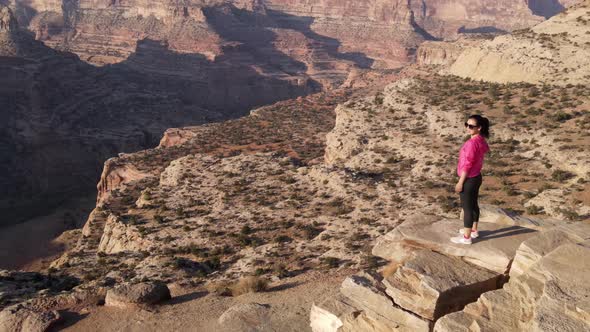 Aerial woman hiking on the edge of the San Rafael River Canyon in Utah