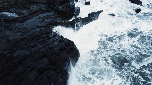 Waves Break on Black Volcanic Rocks in a Blue Ocean Storm in Sea Aerial View Iceland