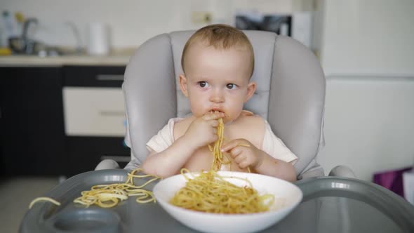 Cute Little Boy Eats Spaghetti with Gusto and Gets Dirty with Red Sauce