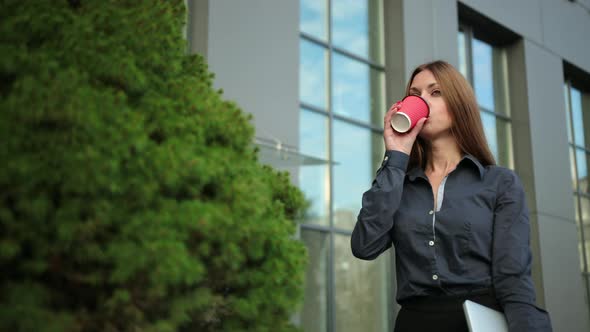 Young Business Woman Drinking a Coffee Laptop in Hand