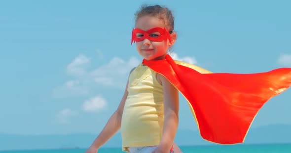 Beautiful Little Girl in the Superhero Costume, Dressed in a Red Cloak and the Mask of the Hero