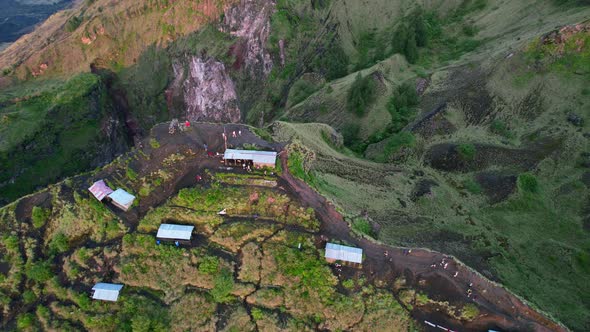 aerial top down of tourists at the cliff of Mount Batur volcano crater rim during sunrise in Bali In