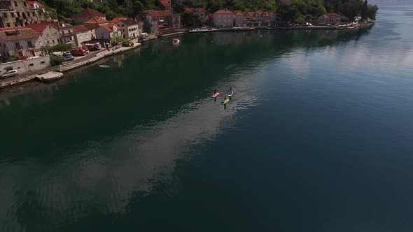 SUP Surfers Sail Along the Kotor Bay Past the Coast of Perast