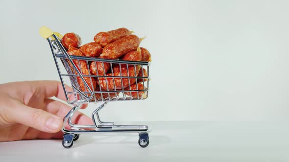 Hand Rolls Out a Small Shopping Trolley with Sausages.