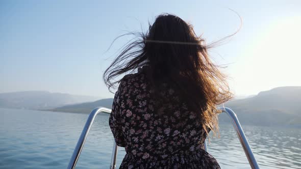 Woman on Boat Bow Sailing Along Lake Against Old Mountains