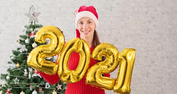 Young Woman in Santa Claus Hat Dancing and Having Fun Holding in Hand Numbers 2021. Girl in