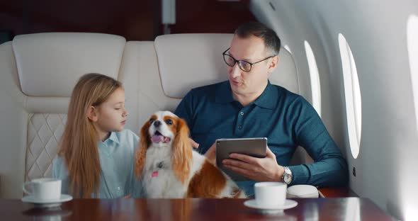 Mature Businessman Travelling on Personal Jet with Little Daughter and Dog