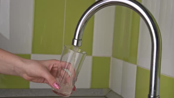 Women's Hands Collect Running Water From the Tap Into a Glass of Slowmo