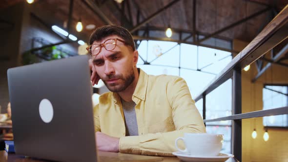 Exhausted Millennial Male Hold Head with Hand Sitting at Office Table Falling Asleep Tired Man Fall