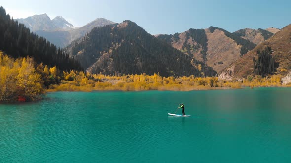Man Is Paddling on Sup Board in the Mountain Lake