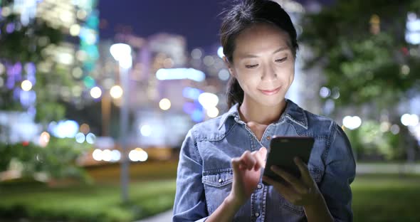 Asian woman use of mobile phone in the city at night 