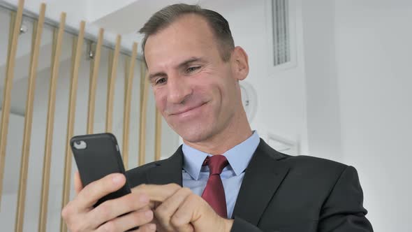 Man Celebrating Success While Using Smartphone