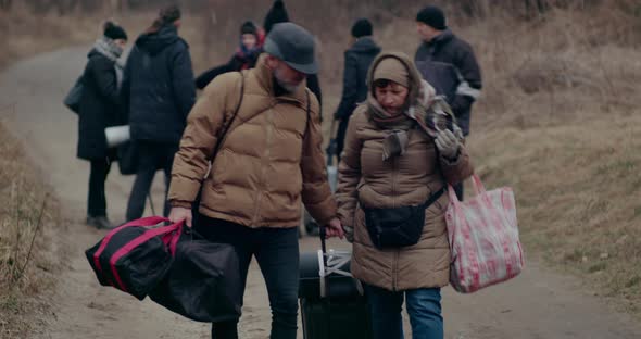 Mature Man Helping Refugee Woman Struggling With Pulling Luggage