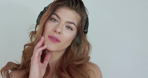 Girl Listening to the Music Caresses Herself and Looks Seductively at Camera
