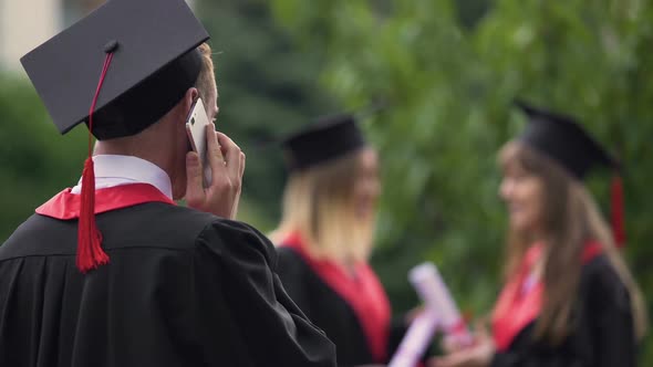 Happy Male Graduate Talking Over Smartphone and Smiling, Graduation Day