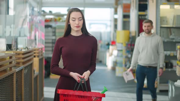 Middle Shot Portrait of Tired Young Caucasian Woman Waiting for Man Standing in Hardware Store