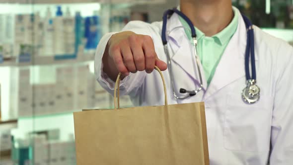 Doctor Smiling and Holding a Package in Drugstore