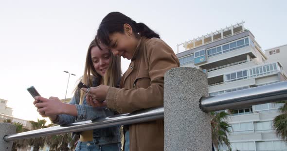 Low angle of a Caucasian and a mixed race girl using their phones