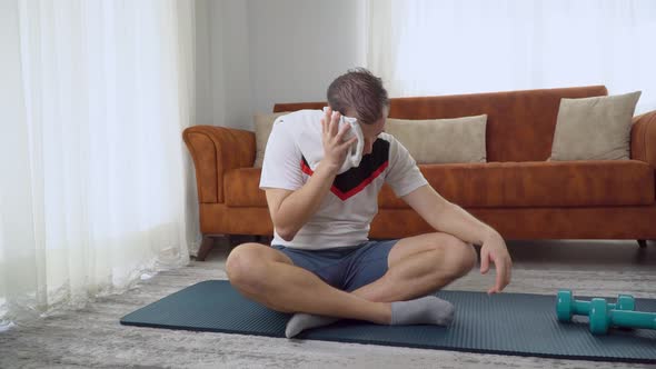 A Man After a Workout Wipes Sweat From His Face with a Towel