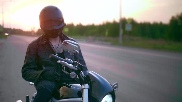 Young Man Sitting on Motorcycle on the Road at Sunset Slow Motion