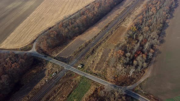 Panoramic View of Railroad Crossing Between Trees Fields Autumn Day Aerial Drone