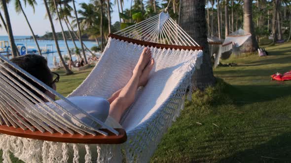 Relaxing Man is Lying in Hammock Near Ocean Coast