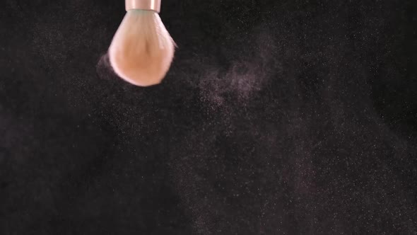 The Brush Shaking and Scattering the Makeup Blush on a Black Background in Slow Motion