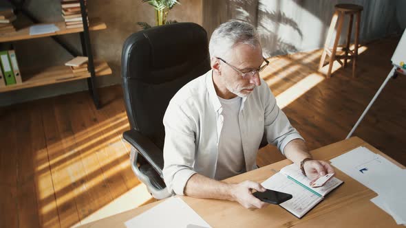 Middleaged Male Holding Credit Card and Entering Its Number Into Smartphone Shopping Online Working