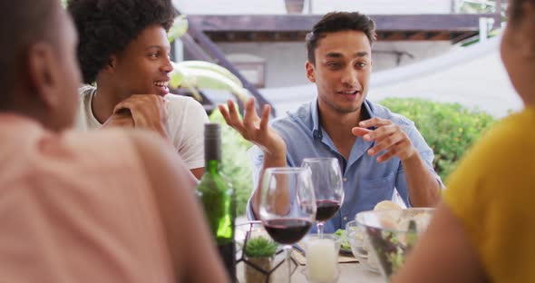 Happy latin man talking with friends at dinner party on patio