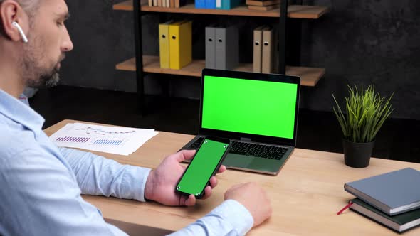 Man Stock Trader Broker Smartphone with Green Display Laptop with Green Screen