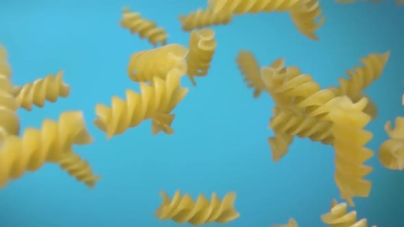 Dry Pasta Fusili Flying Diagonally on the Sky Blue Background