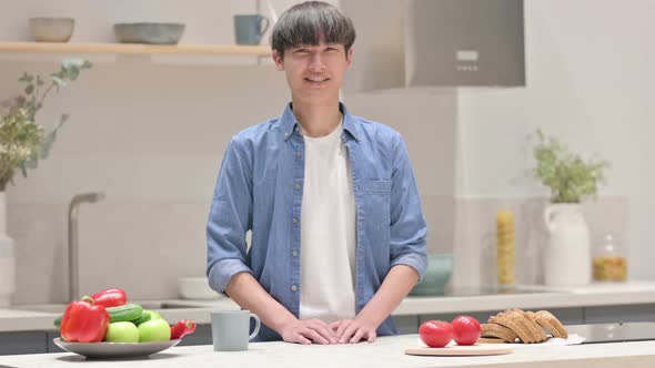 Young Asian Man Smiling at the Camera While Standing in Kitchen