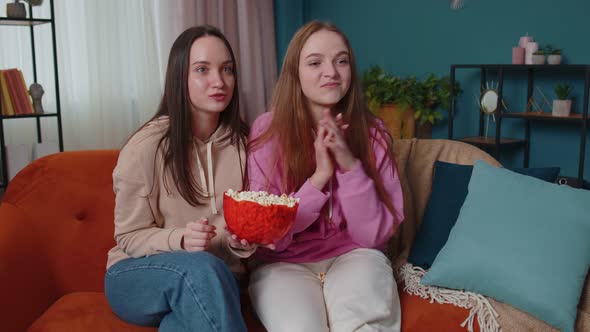 Two Girls Friends Siblings Watching Favorite Tv Show Movie Eating Popcorn Sitting on Sofa at Home