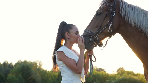 Young Woman Brunette with Hair in Ponytail Pets Brown Horse