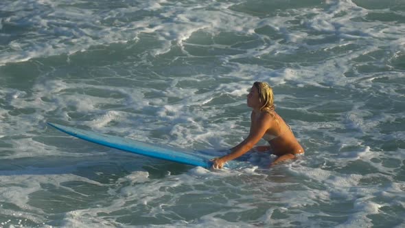 A young woman surfing in a bikini on a longboard surfboard.